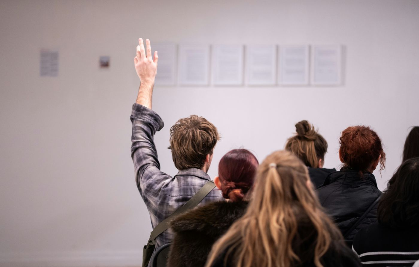 An audience member raising a hand to ask a question